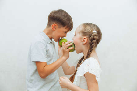 a boy and a girl are eating apples in the dentist's chair. the concept of healthy teeth. children eat a green apple.の写真素材