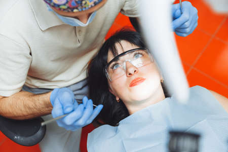 A male doctor examines the oral cavity of a young patient sitting in a dentist's chair in the office next to the dentist. the concept of healthy teeth.の写真素材