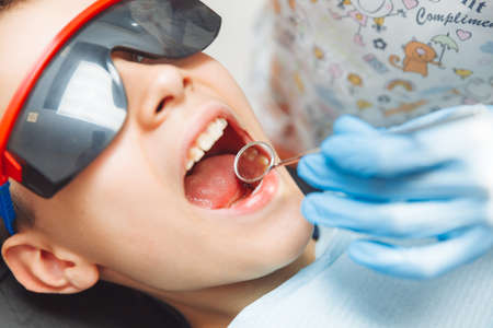 The dentist examines the teeth of a boy of 13 years old in the clinic. pediatric dentistryの写真素材