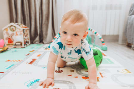 A little boy is playing with a ball on the mat at home. The concept of children's development, sports, education and creativity at homeの写真素材