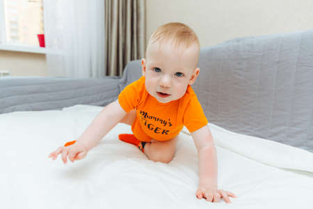 baby in a diaper crawls on the couch. baby is 11 months old.