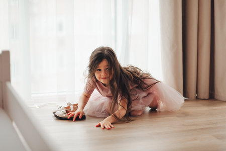 the little girl took off her shoes and sat down to rest near the window on the warm floor. cozy and comfortable house.の写真素材