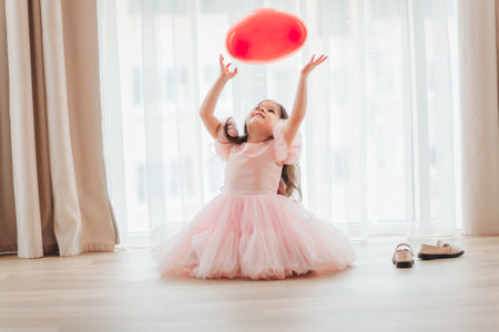 valentine's day baby. A little girl in a red dress holds a large ball in the shape of a heartの写真素材