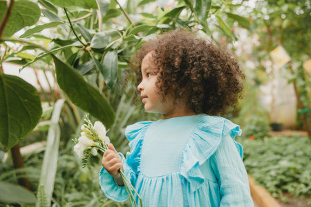 little girl surrounded by tropical leaves. Portrait of a swarthy child with dark hair. Natural cosmetics, health, cleanlinessの写真素材