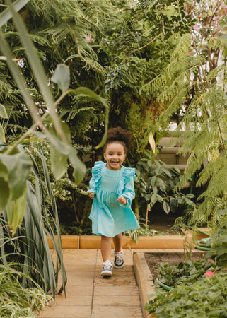 A little girl in a white dress runs along the path in the botanical garden.の写真素材