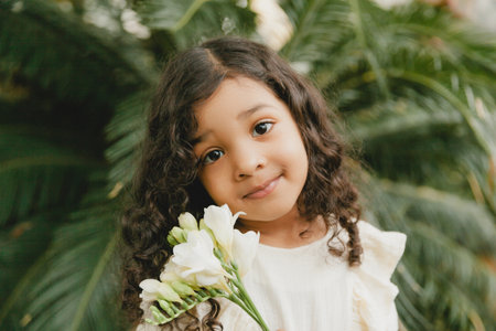 little girl surrounded by tropical leaves. Portrait of a swarthy child with dark hair. Natural cosmetics, health, cleanlinessの写真素材