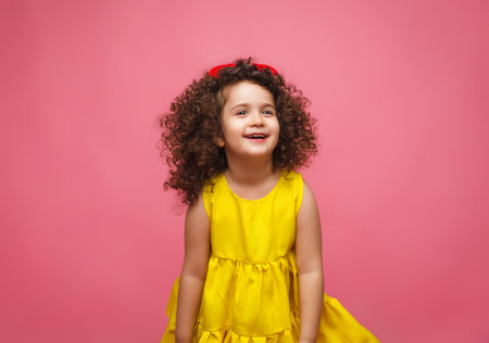 portrait of a girl in a yellow dress cute attractive cute cheerful cheerful little girl .isolated pink background.の写真素材