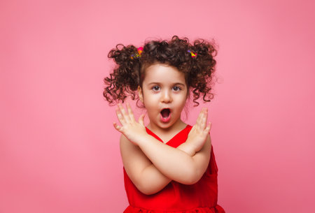 emotional portrait of a little girl in a red dress on a pink background.の写真素材