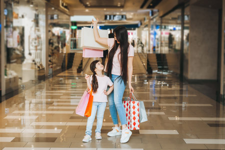 young mother and daughter holding shopping bags, shopping in the mall. family shopping.の写真素材