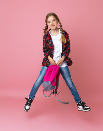 Full length photo of jumping schoolgirl with pink backpack laughing on isolated pastel pink...
