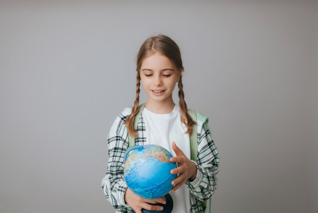Caucasian young teenager schoolgirl student holding a globe on a gray background, isolated. happy earth dayの写真素材