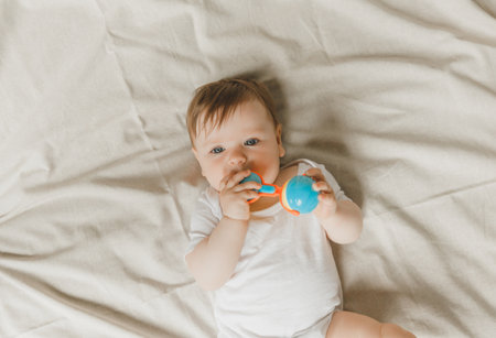A baby with a teether and a rattle on a cotton bed. Teething. children's article. copy space