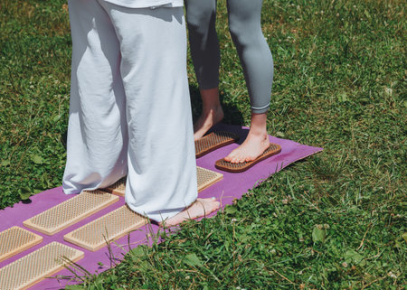 A woman is standing on a sadhu board. Close-up of legs.yoga nails in nature.の写真素材