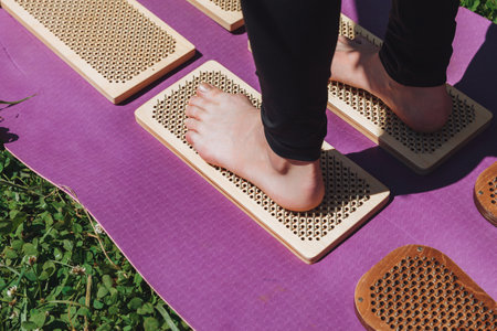 A woman is standing on a sadhu board. Close-up of legs.yoga nails in nature.の写真素材