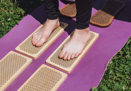 A woman is standing on a sadhu board. Close-up of legs.yoga nails in nature.