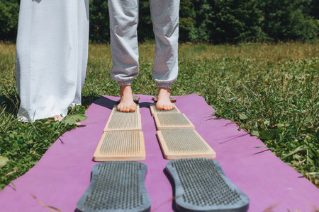 A woman is standing on a sadhu board. Close-up of legs.yoga nails in nature.の写真素材