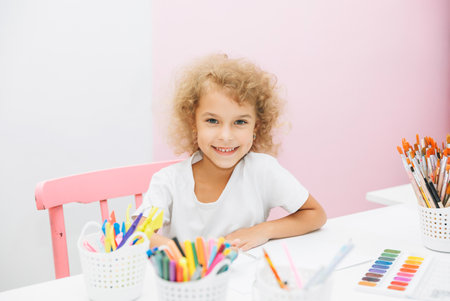 Cute little blonde preschooler girl draws at home