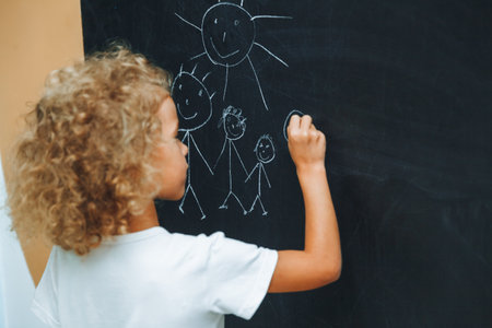 Little girl draws a family on a chalkboard