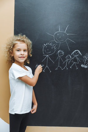 Little girl draws a family on a chalkboardの写真素材