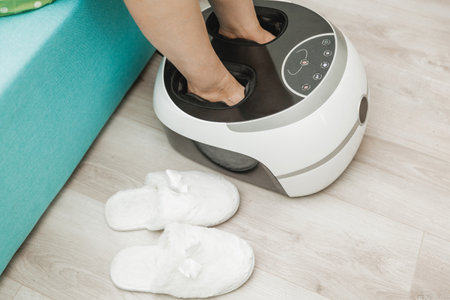 woman sits on the sofa and uses a foot massager for relaxation, which helps relieve pain and improve blood circulation.の写真素材
