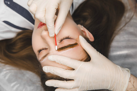 A cosmetologist applies permanent makeup to the eyebrows - eyebrow tattoo. eyebrow perm