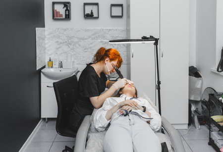 A cosmetologist applies permanent makeup to the eyebrows - eyebrow tattoo. eyebrow permの写真素材