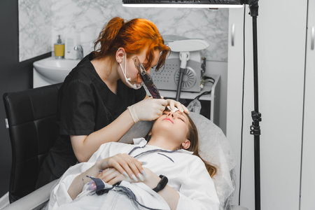 A cosmetologist applies permanent makeup to the eyebrows - eyebrow tattoo. eyebrow permの写真素材