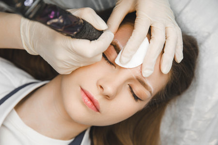 A cosmetologist applies permanent makeup to the eyebrows - eyebrow tattoo. eyebrow permの写真素材