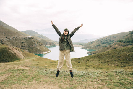 A cheerful girl is jumping against the backdrop of a mirror lake and mountains. Soft focus. Lake...