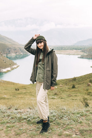 a girl standing on the edge of a mountain and a lake behind her. Caucasus