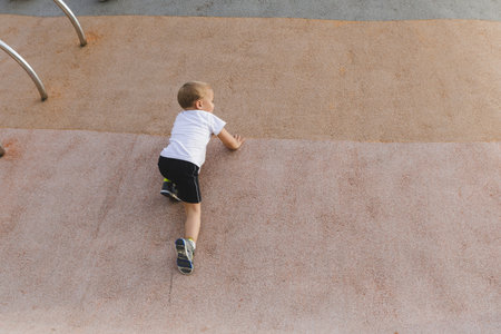 little boy climbing stone wall on playground. sport life concept