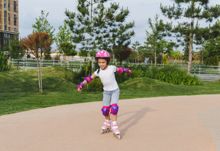 A little curly-haired girl rollerskates within the necessary facilities in the city. In a helmet and armbandsの写真素材