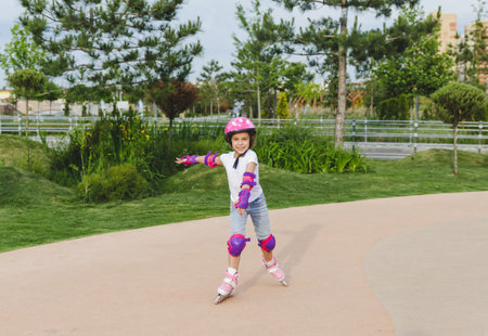 A little curly-haired girl rollerskates within the necessary facilities in the city. In a helmet and armbandsの写真素材