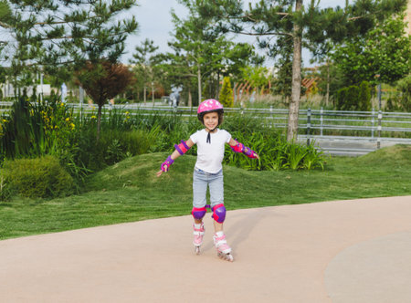 A little curly-haired girl rollerskates within the necessary facilities in the city. In a helmet and armbandsの写真素材