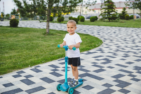 A boy of 4-5 years old rides a scooter in a city park.の写真素材