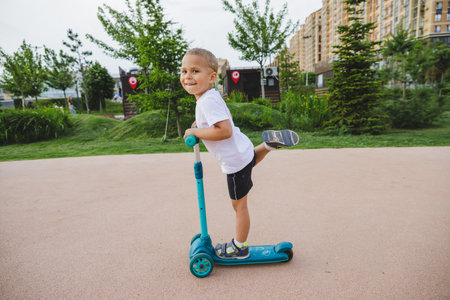 A boy of 4-5 years old rides a scooter in a city park.の写真素材