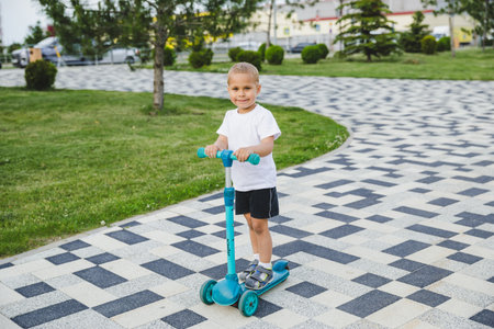 A boy of 4-5 years old rides a scooter in a city park.の写真素材