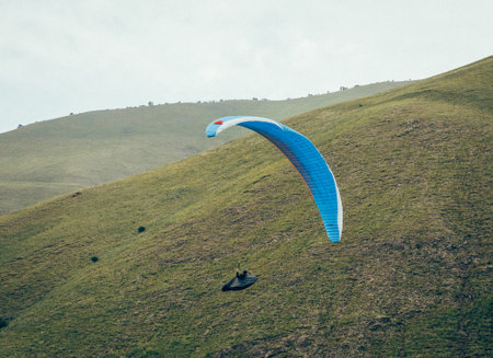 Paragliding against the backdrop of a clear blue sky and mountains.Papraplans in Chegem,...