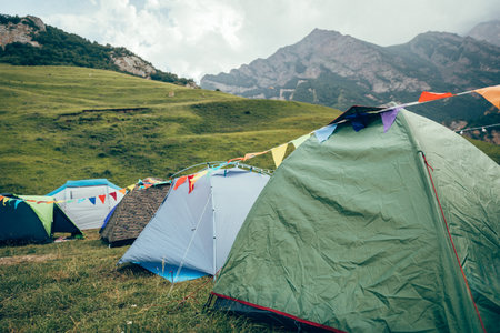 Camping in the mountains with colorful flags and tentsの写真素材