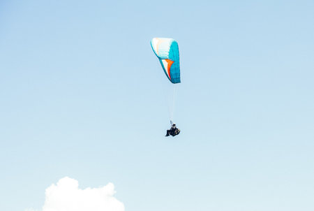 Paragliding against the backdrop of a clear blue sky and mountains.