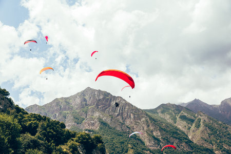 High altitude paragliding. Many colorful paragliders in the sky against the picturesque backdrop of...