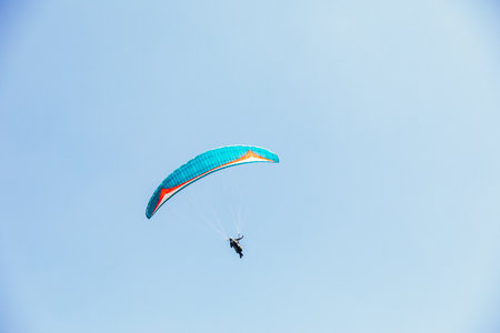 Paragliding against the backdrop of a clear blue sky and mountains. Paragliding in Chegem,...