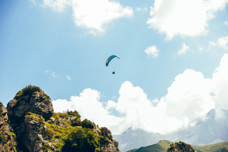 Paragliding against the backdrop of a clear blue sky and mountains.Papraplans in Chegem,...