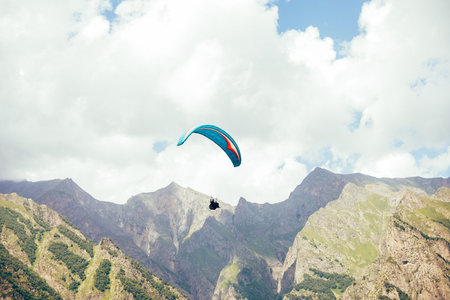 Paragliding against the backdrop of a clear blue sky and mountains. Paragliding in Chegem,...