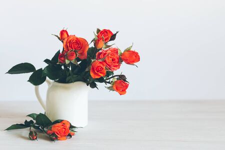 Romantic bouquet  of bright red orange roses in a jar on a white background. Place for text.の写真素材