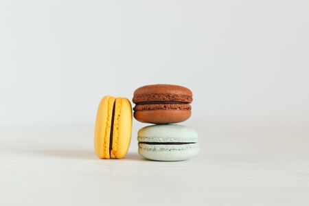 Three French macarons on a white wooden table. Multicolored macarons. White background. Minimal concept, place for text.の写真素材