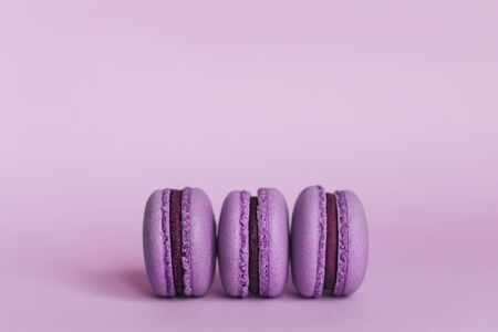 Three purple french macarons on a purple background. Place for text. Close up.の写真素材