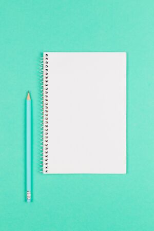 Notebook with blank page and pencil on turquoise background. Flat lay. Place for text. の写真素材