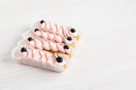 Tasty French eclairs with cream and fresh berries on white wooden table. Set of delicious eclairs. Selective focus. Place for text.の写真素材
