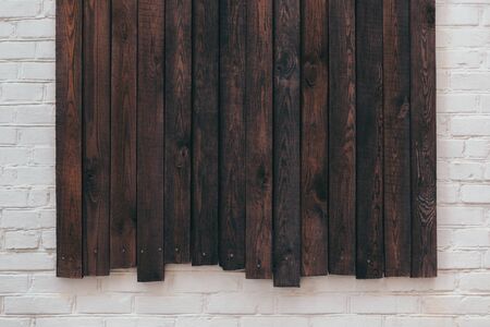 Dark rustic wooden boards on white brick wall.  Wooden background.  Place for text. の写真素材